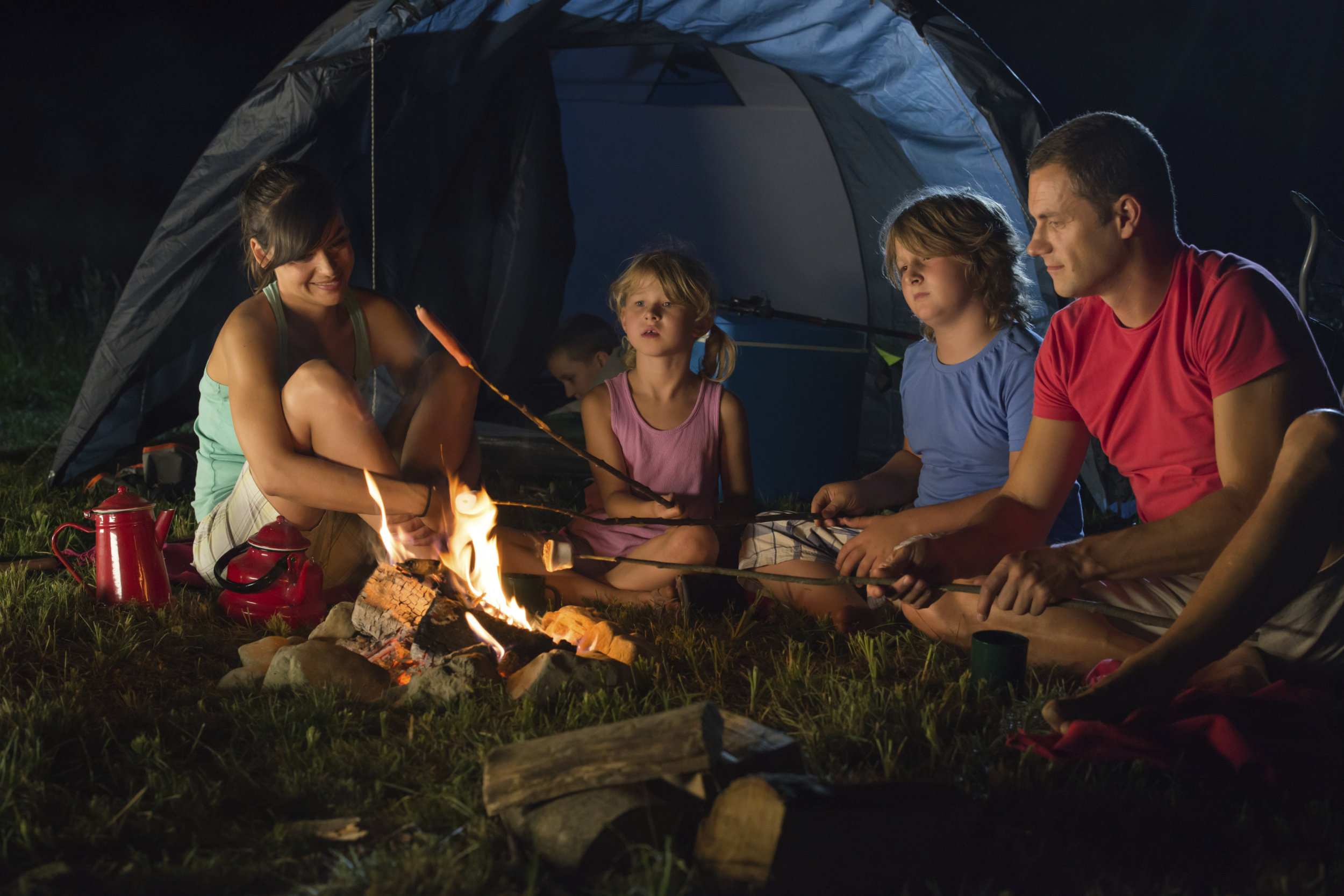 Family roasting marshmallows by tent